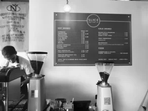 Slice café menu board on the wall behind coffee grinders