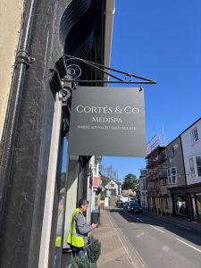 Cortes & Co Medispa hanging sign on a bracket above a street