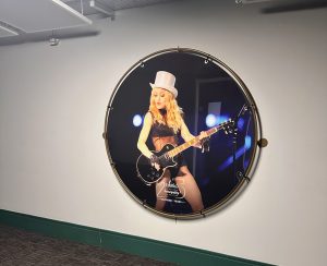 Circular framed wall art of a guitarist on stage in a corridor
