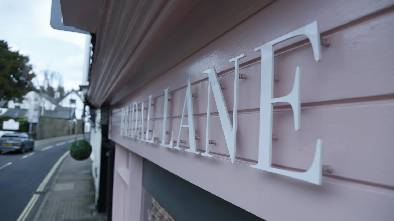 Raised white house-name lettering fixed to pink timber cladding