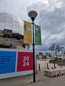 Lamp-post banners and 2024 hoarding graphics on a waterfront